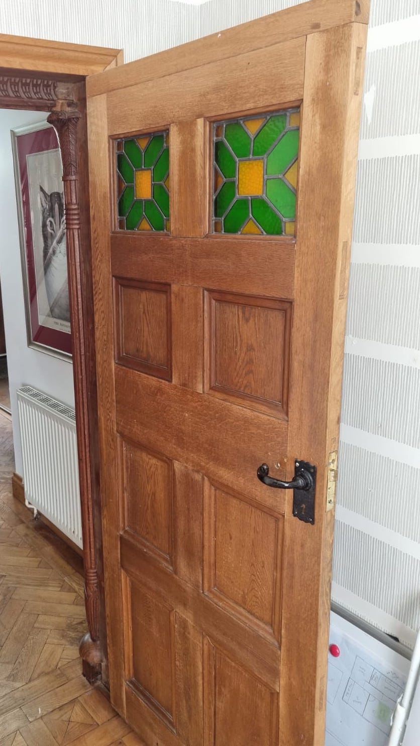 A panelled oak door with inset stained glass panels, width 78cm, height 194cm, another panelled door, sundry framework and assorted columns
